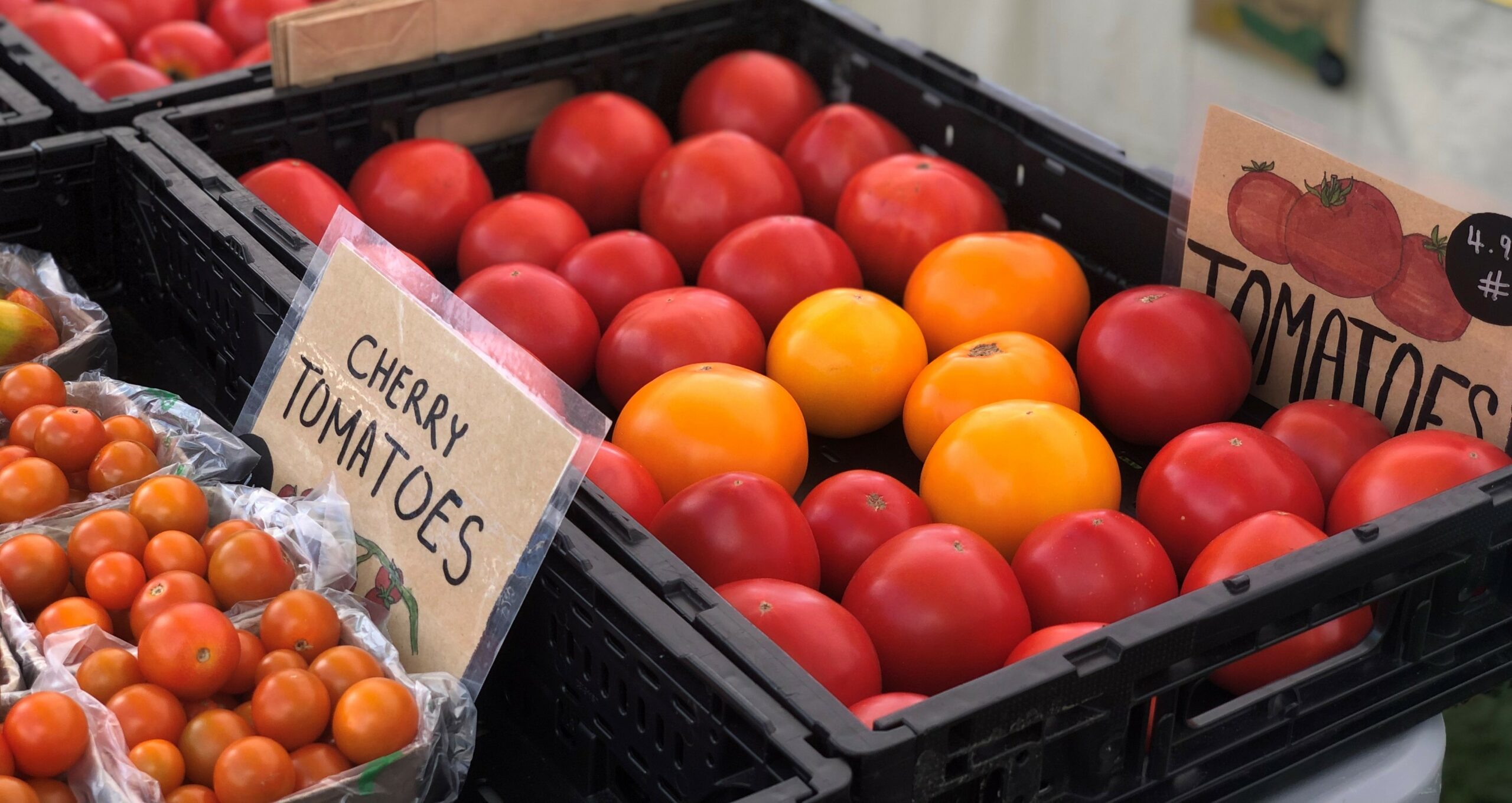 Packages of cherry tomatoes and a crate of red and yellow tomatoes.